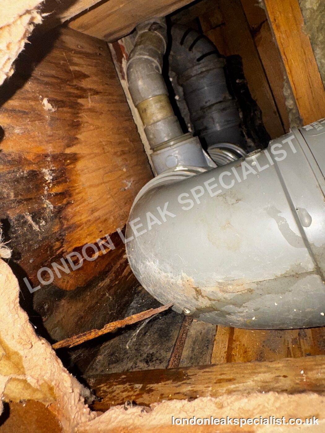 Soil stack and branch pipes in a void with dark water staining on the surrounding timber